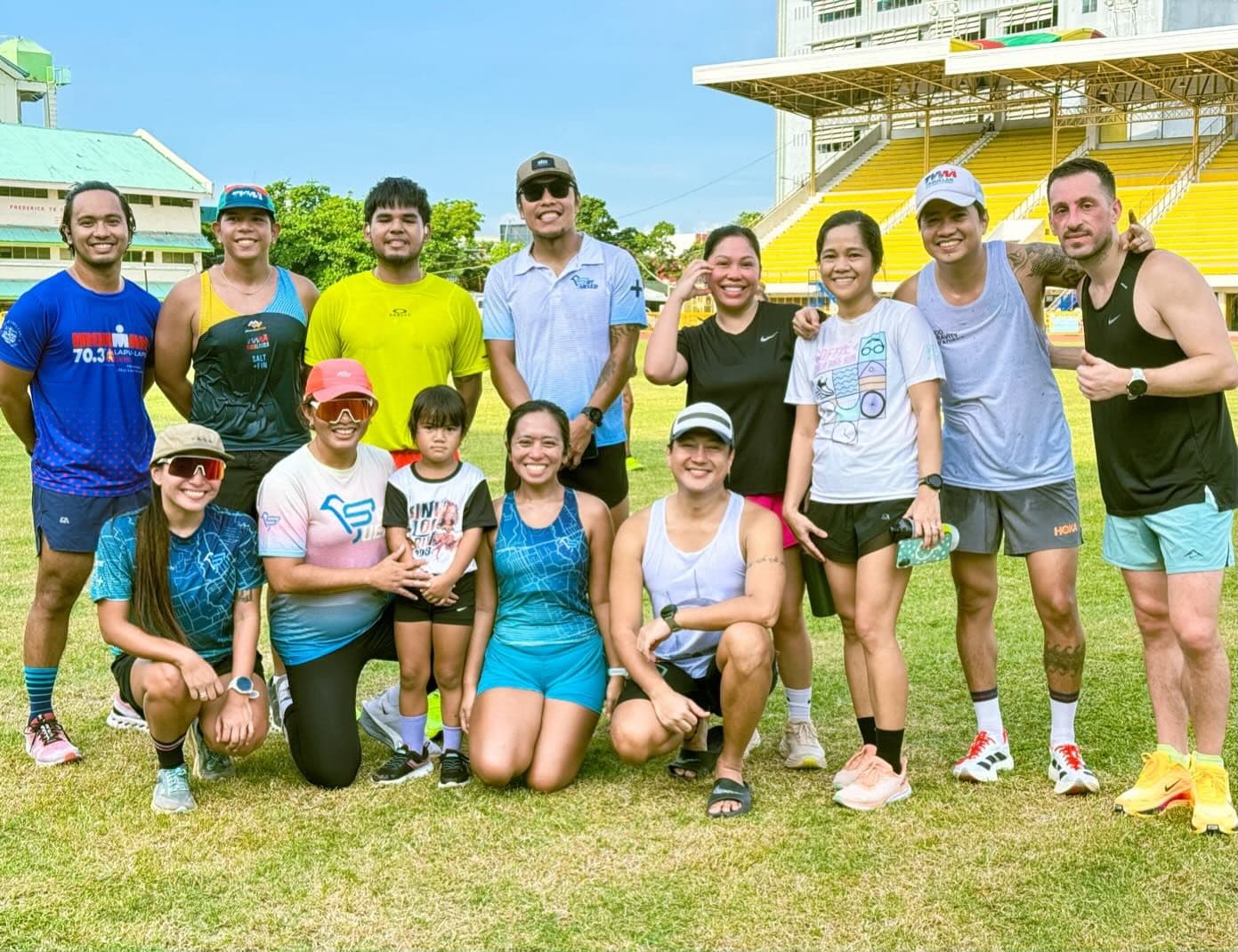 A mixed group of athletes and friends posing on a grass field