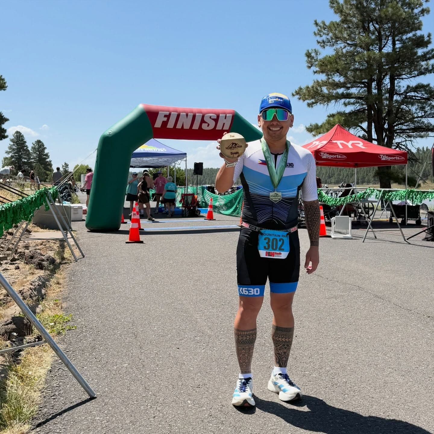 Athlete showing a medal in front of a green FINISH arch