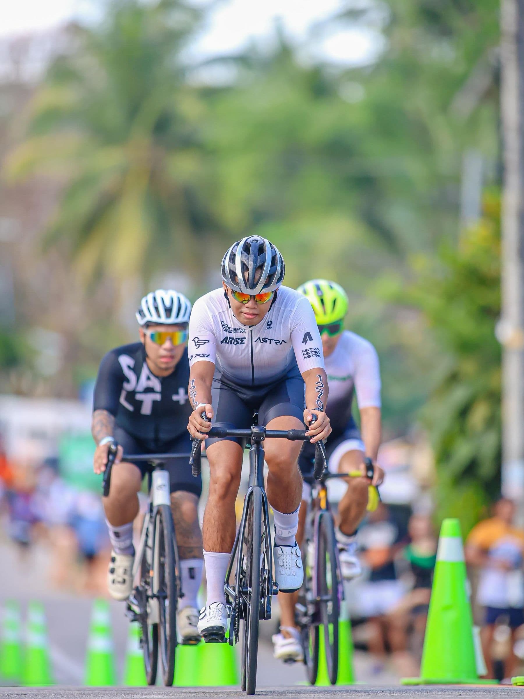 Three cyclists in helmets and sunglasses riding close together during a race