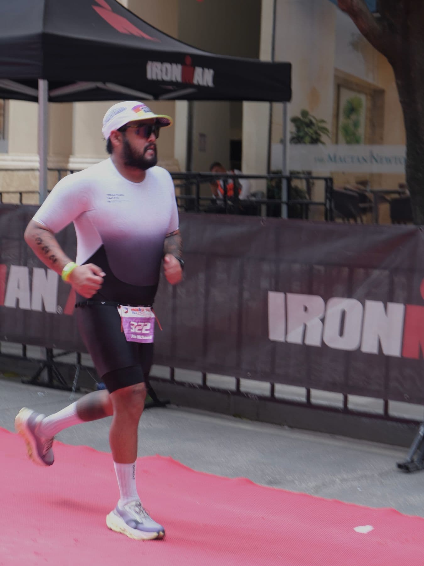 Triathlete running on the red carpet beside IRONMAN barriers