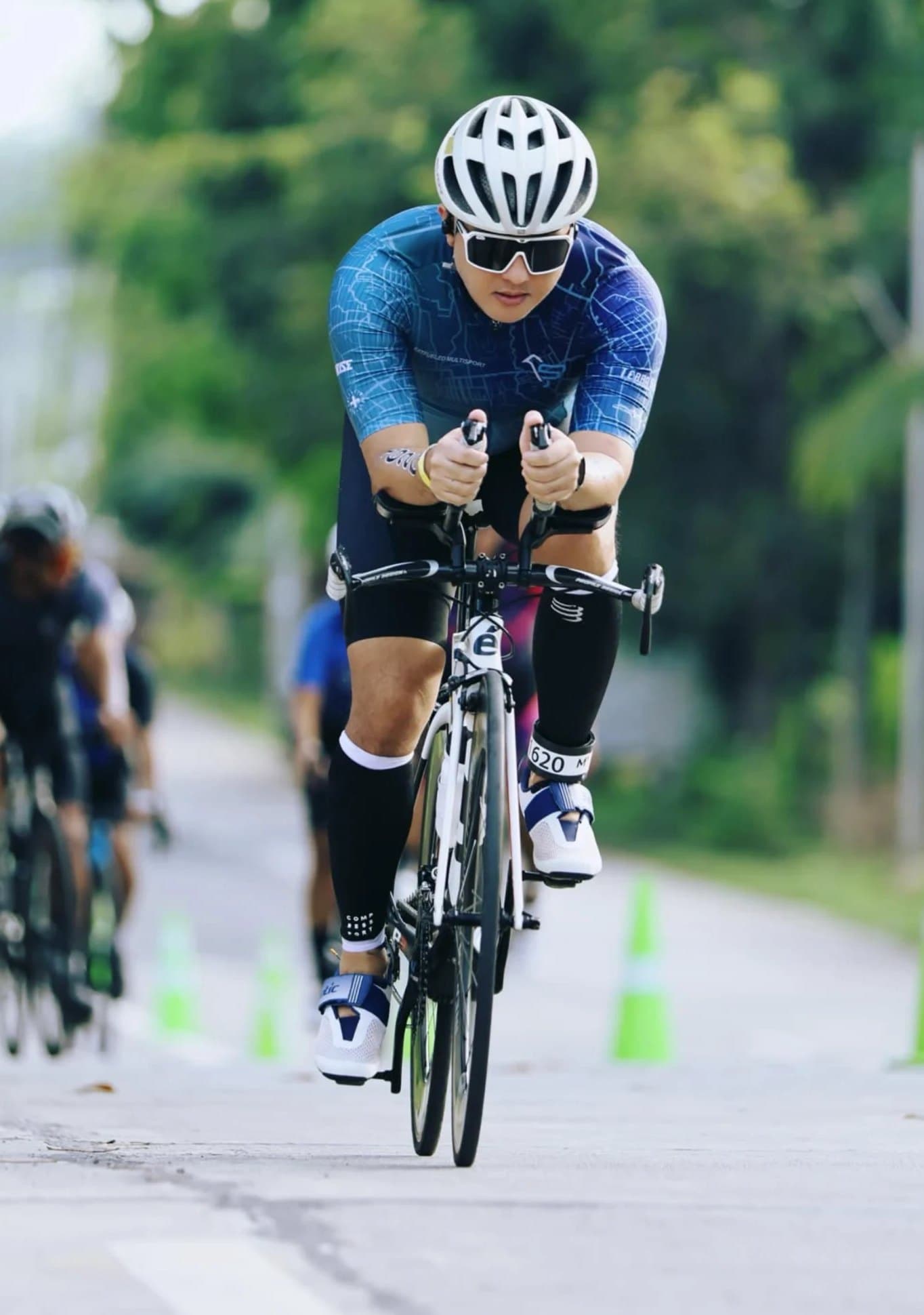 Triathlete in a Fat Fueled Multisport kit riding on aero bars during a race
