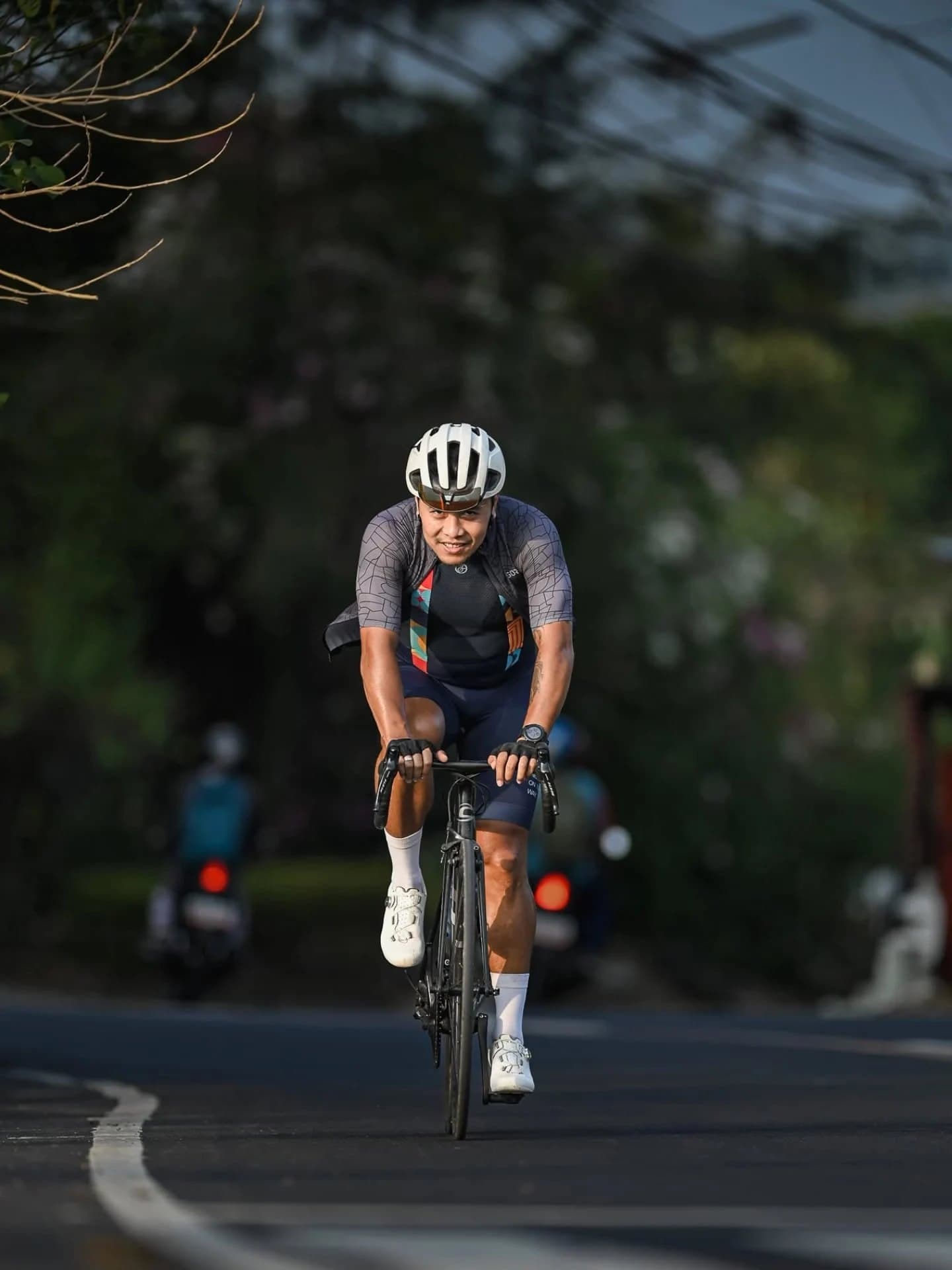 Coach Lee Stephen Fat riding his road bike along a tree-lined road
