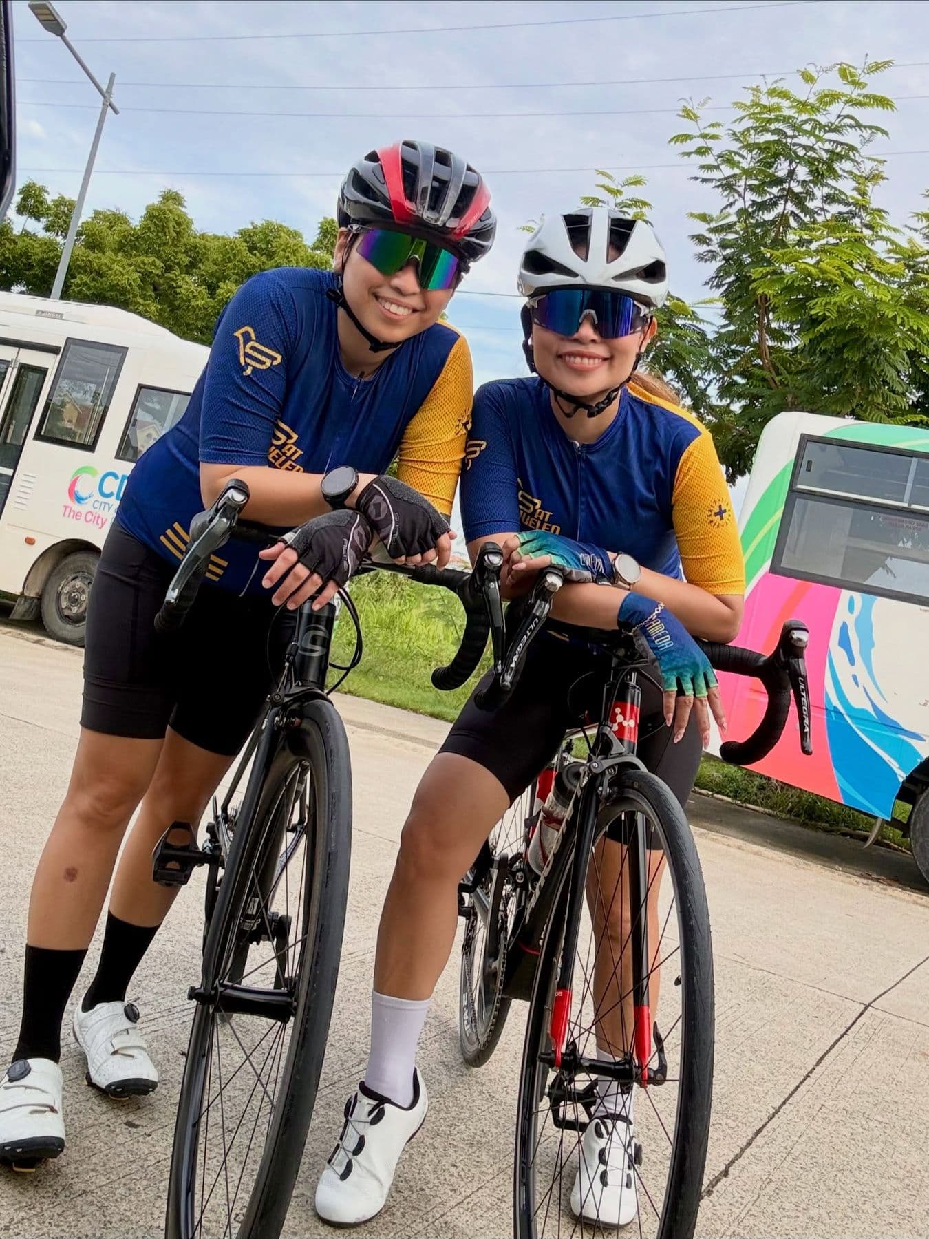 Two cyclists in matching kits posing with their road bikes