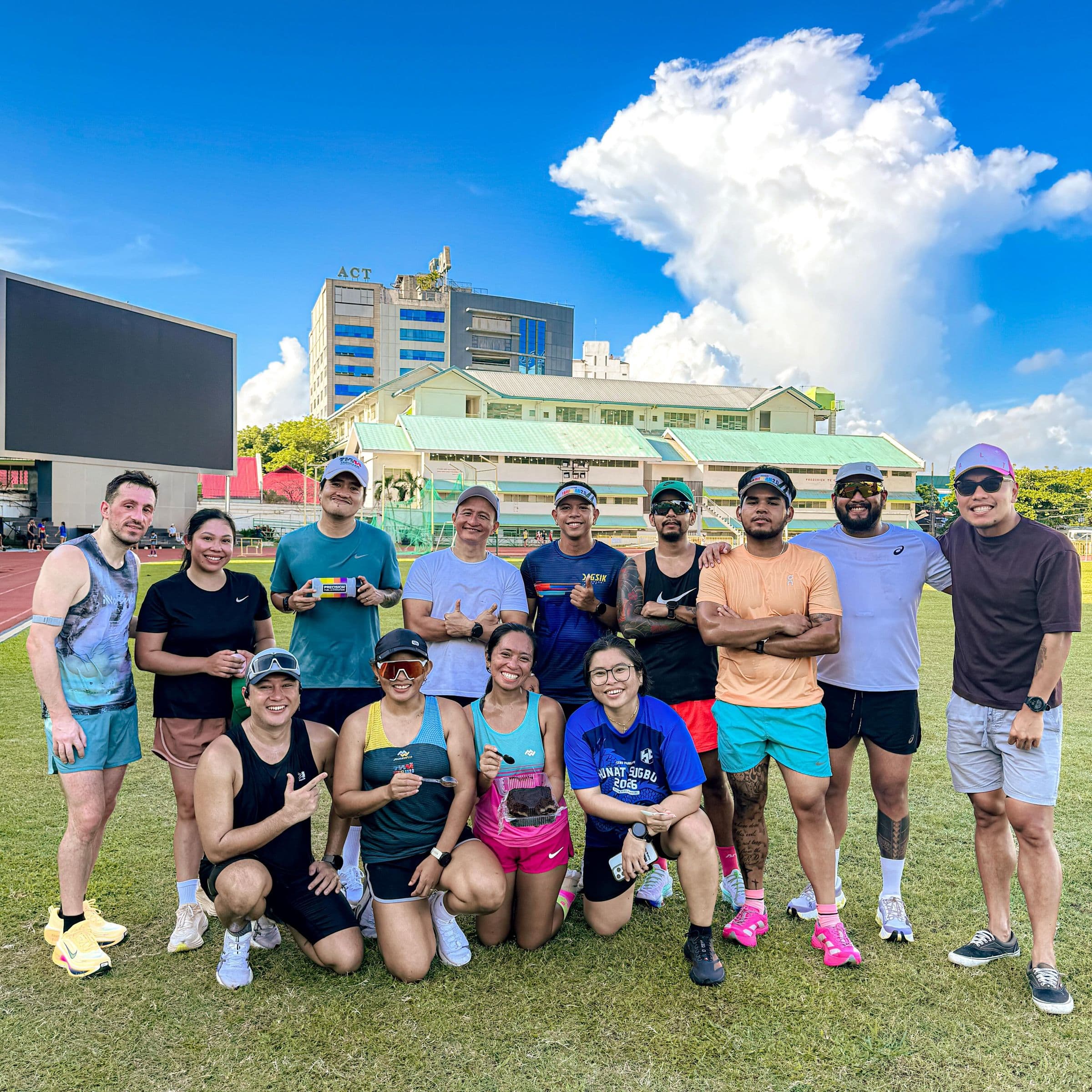 A large group of athletes posing together on a sunny sports field