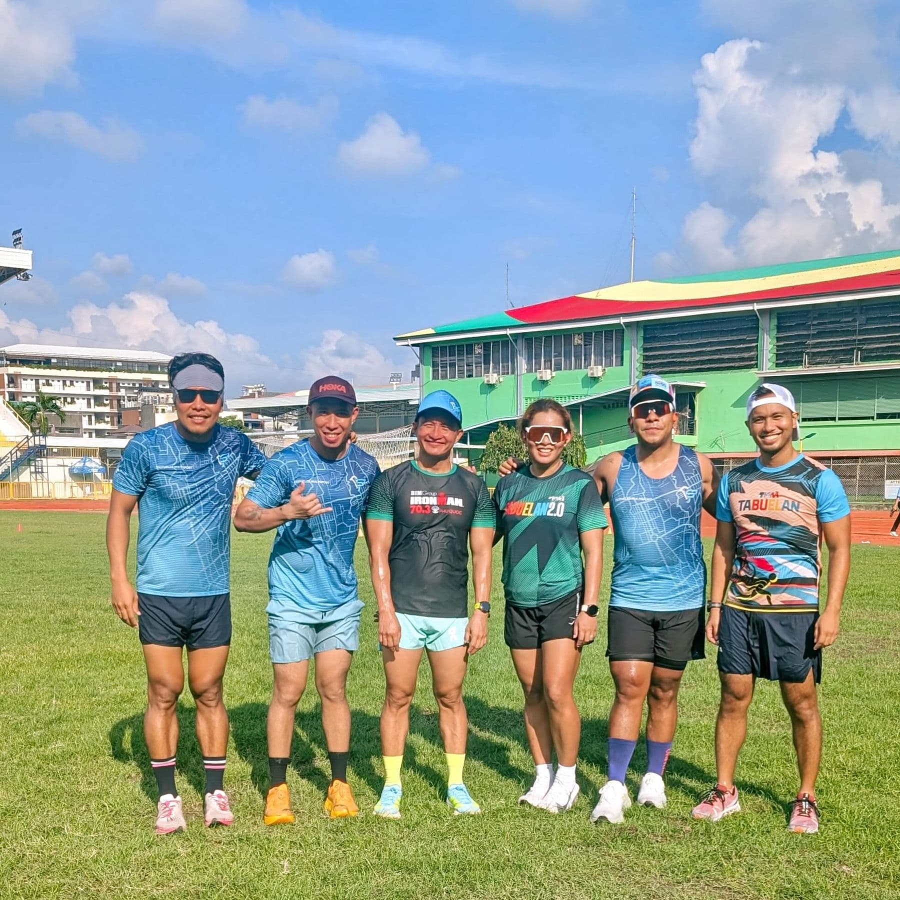 Six athletes in race shirts standing together on a sports field