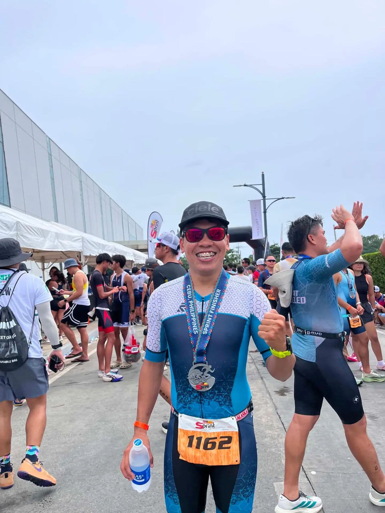 Smiling athlete in a trisuit wearing a finisher's medal after a race