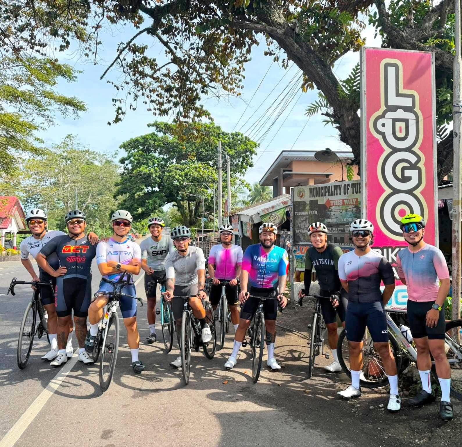 A group of cyclists lined up with their bikes on a roadside before a ride