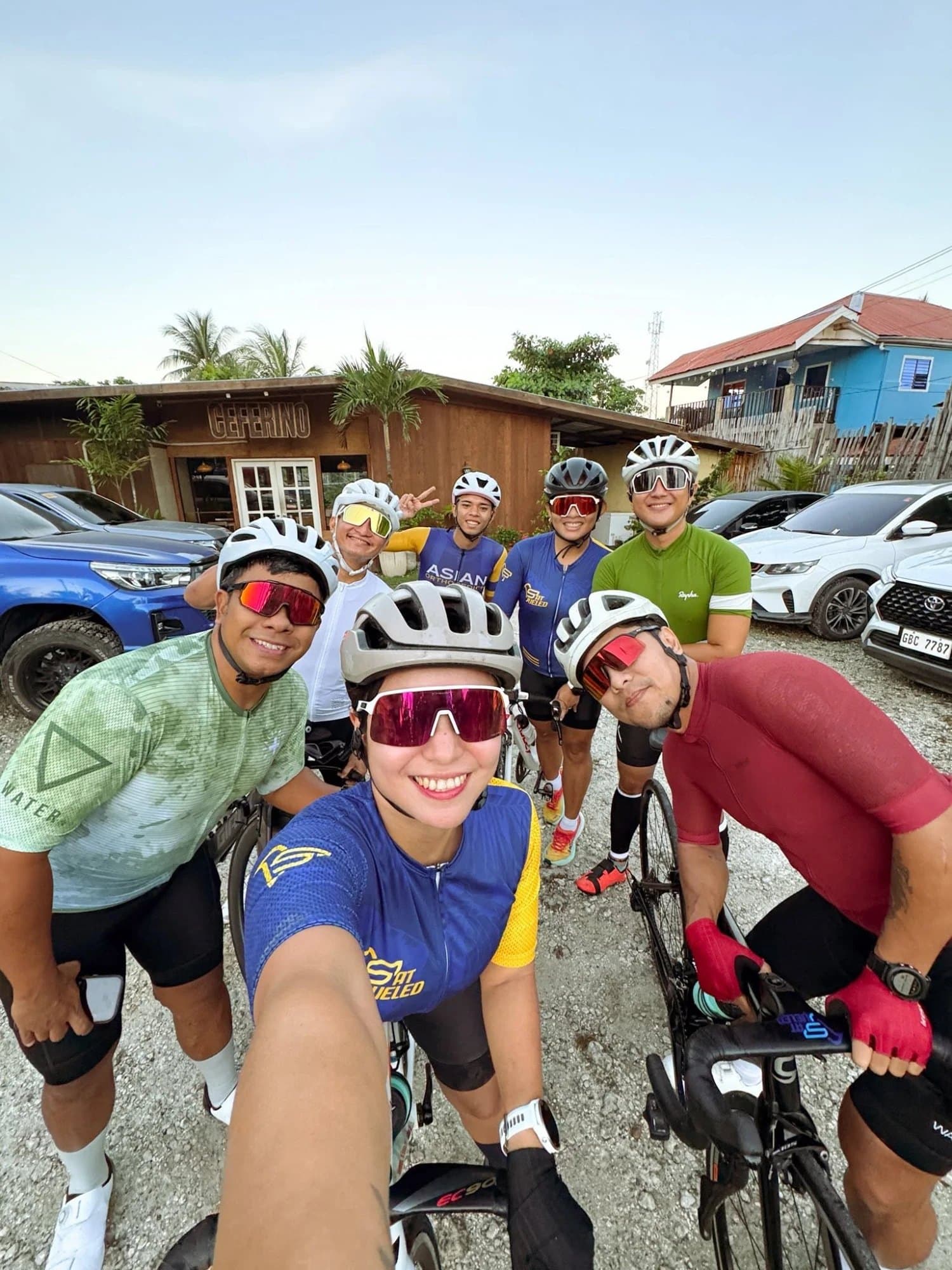Smiling Fat Fueled cyclists in helmets and sunglasses taking a group selfie before a ride