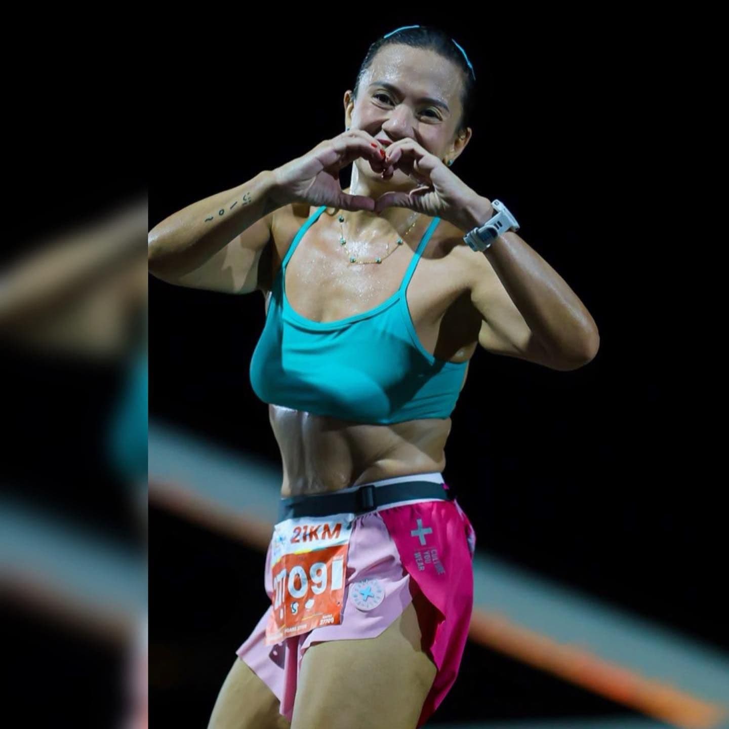 Runner making a heart shape with both hands under the race lights