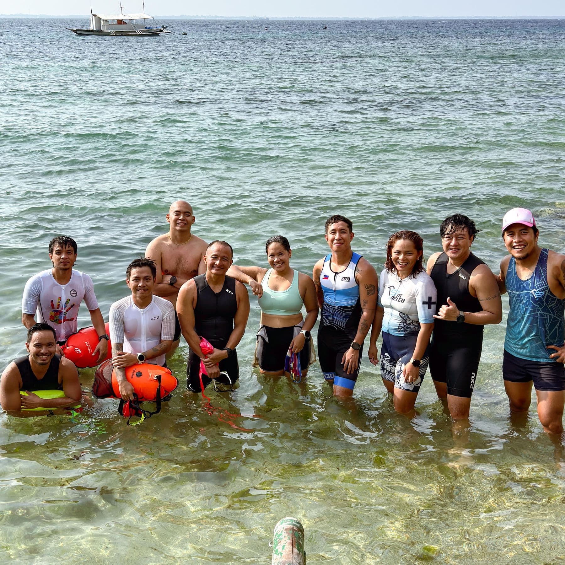 Group of swimmers standing waist-deep in the sea with orange tow floats
