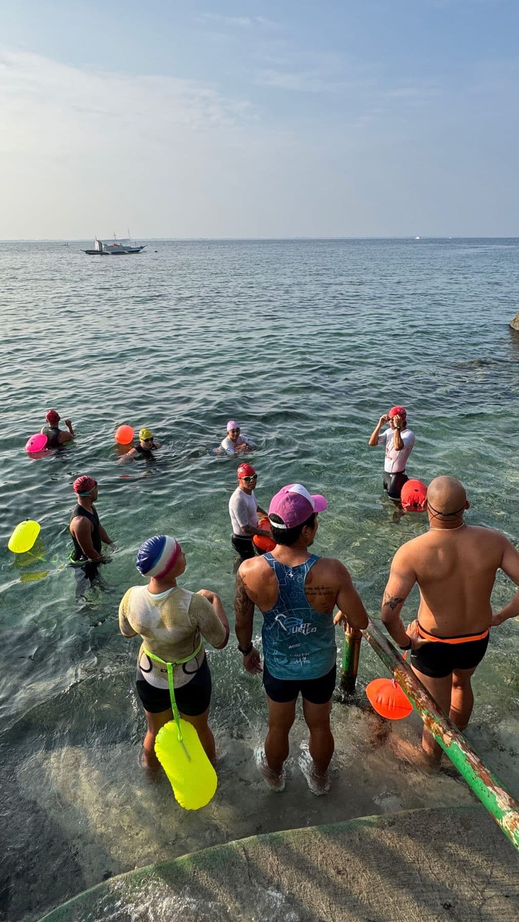 Swimmers with tow floats gathering in clear water for an open-water session