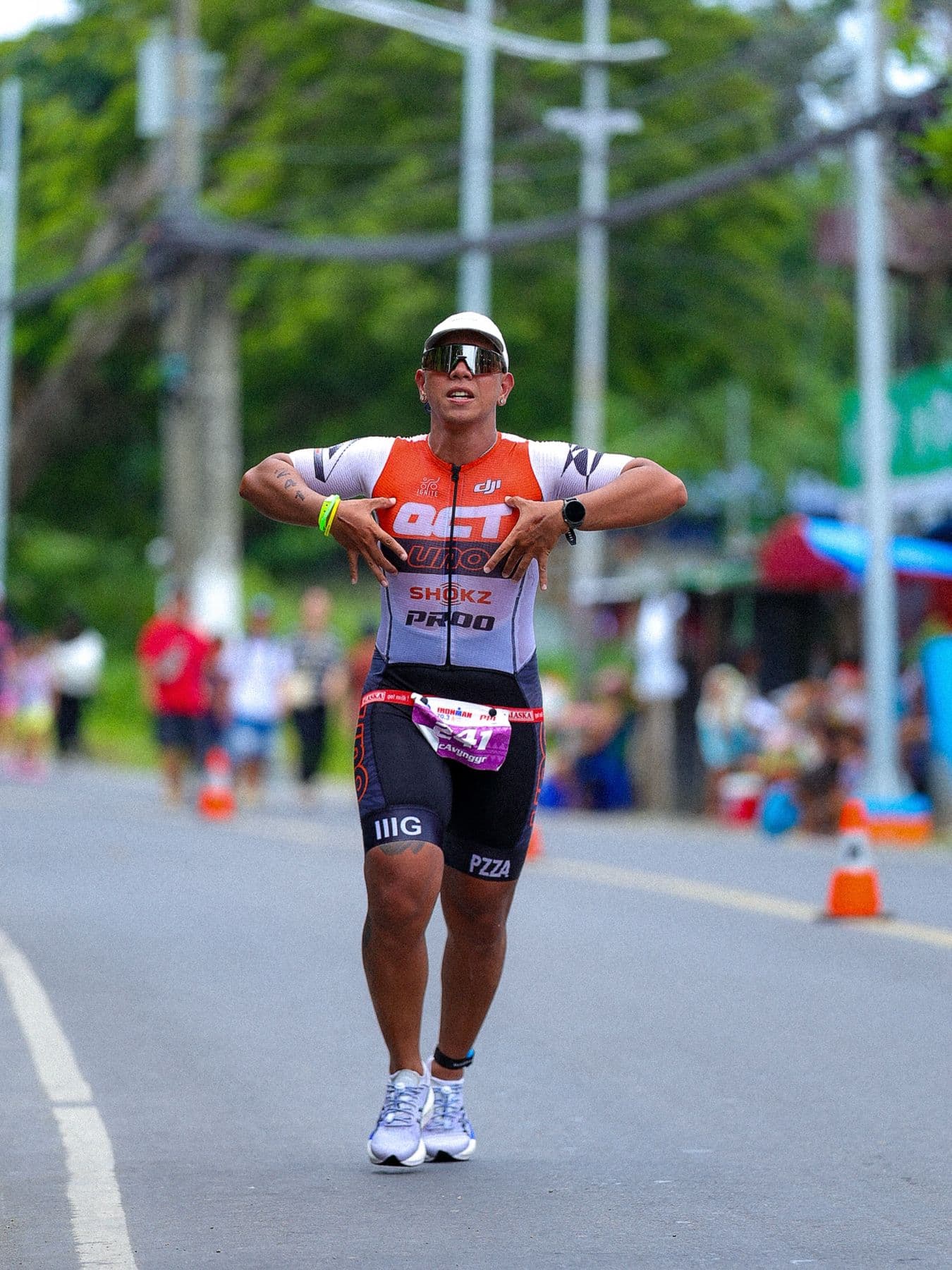 Runner in an orange-and-white kit gesturing to the camera mid-race