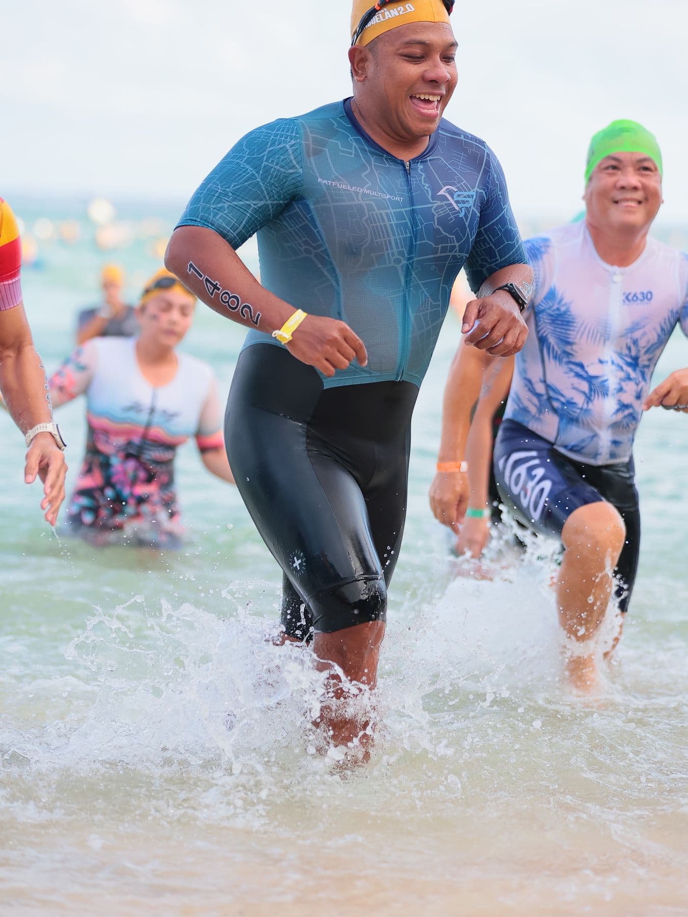 Smiling triathlete splashing out of the sea with other swimmers