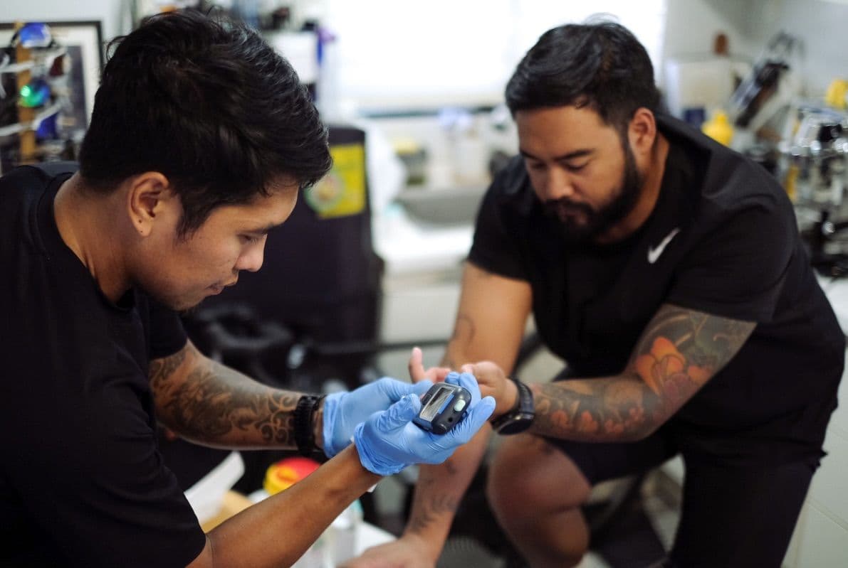 Gloved hands taking a fingertip sample from an athlete during a testing session